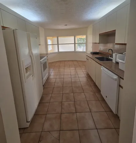 a kitchen with granite countertop a refrigerator a sink a stove a microwave and cabinets