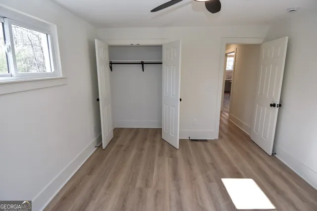 a view of an empty room with wooden floor and a window