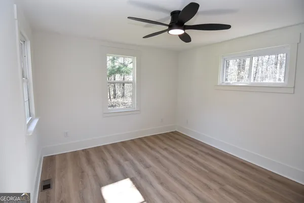 an empty room with wooden floor and windows