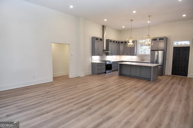 a kitchen with stainless steel appliances granite countertop a refrigerator a oven a sink and a dining table with wooden floor