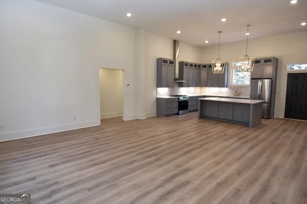 a kitchen with stainless steel appliances granite countertop a refrigerator a oven a sink and a dining table with wooden floor