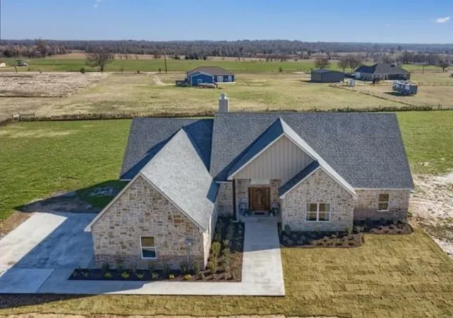 an aerial view of a house with a yard and ocean view