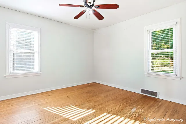 a view of a big room with wooden floor and windows