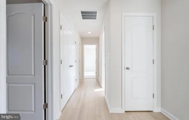 a view of a hallway with wooden floor and closet area