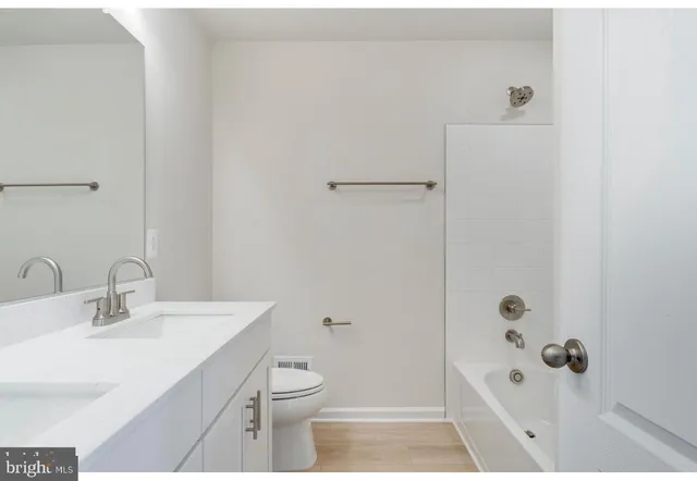 a bathroom with a bathtub shower sink mirror and toilet