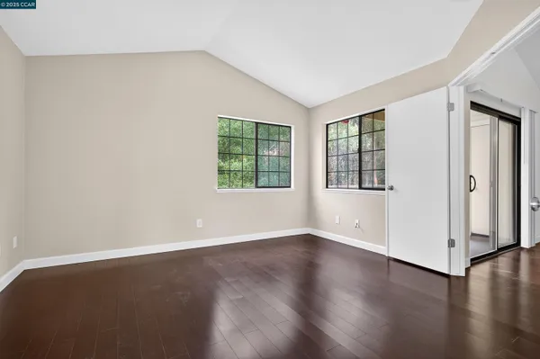 an empty room with wooden floor and windows