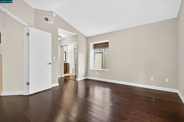 a view of an empty room with wooden floor and a window