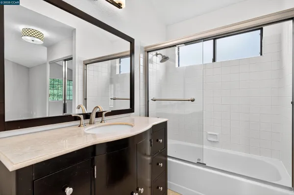 a bathroom with a shower sink vanity and mirror