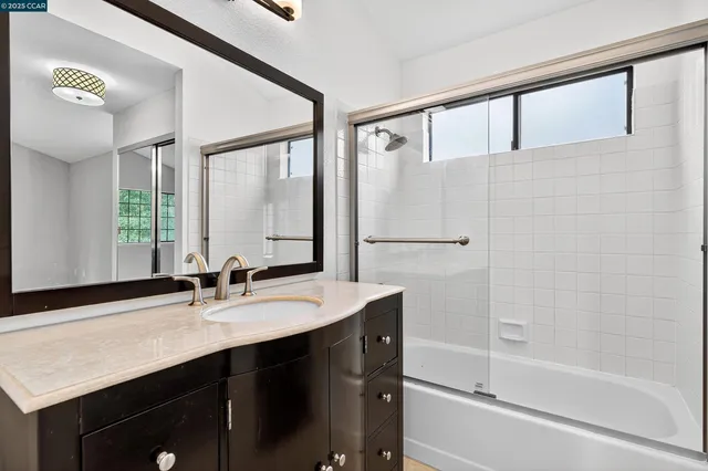 a bathroom with a shower sink vanity and mirror