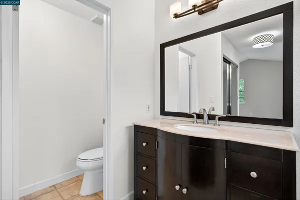 a bathroom with a granite countertop sink toilet and mirror