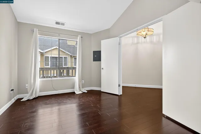 an empty room with wooden floor and windows