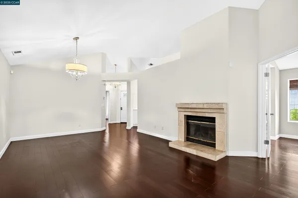 an empty room with wooden floor fireplace and windows