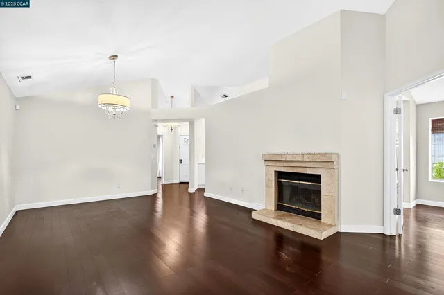 an empty room with wooden floor fireplace and windows