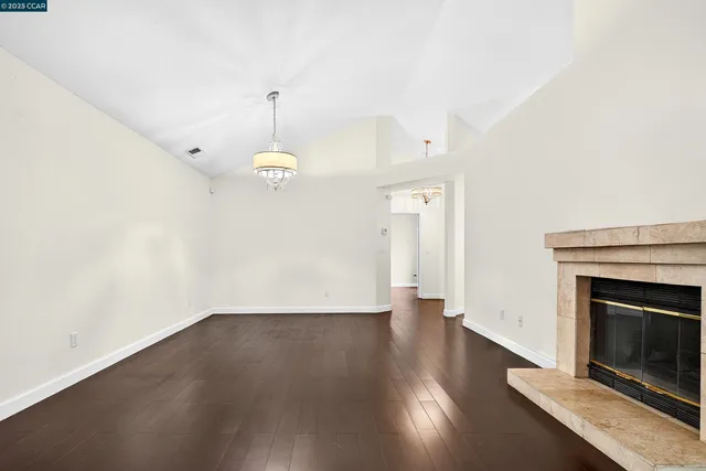 an empty room with wooden floor fireplace and windows