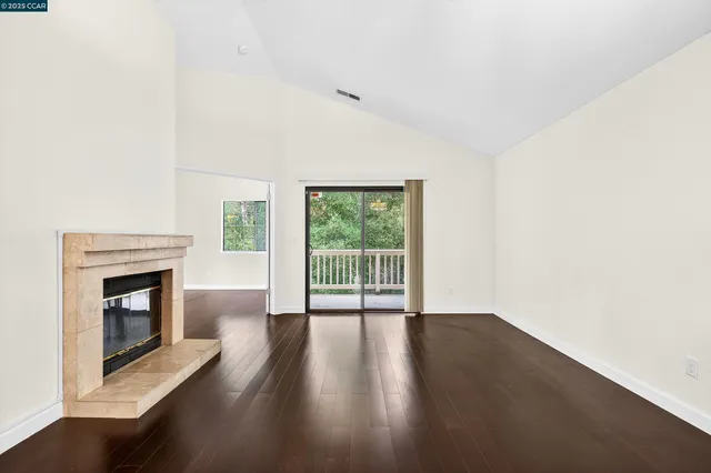 a view of empty room with wooden floor and fireplace