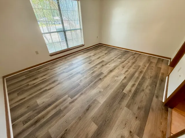 a view of empty room with wooden floor and fan