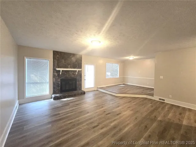 an empty room with wooden floor and fireplace
