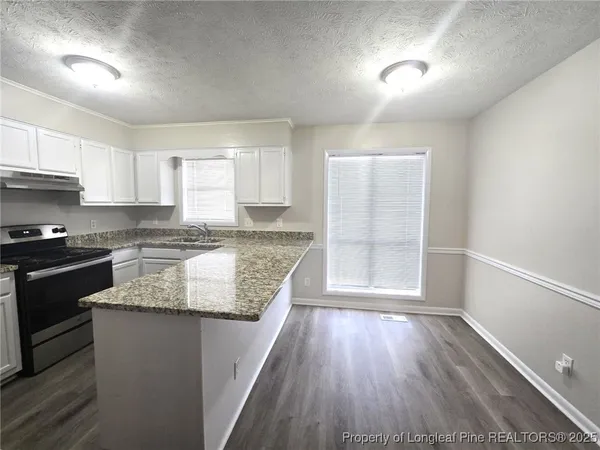 a kitchen with granite countertop wooden floors a stove and a granite counter tops