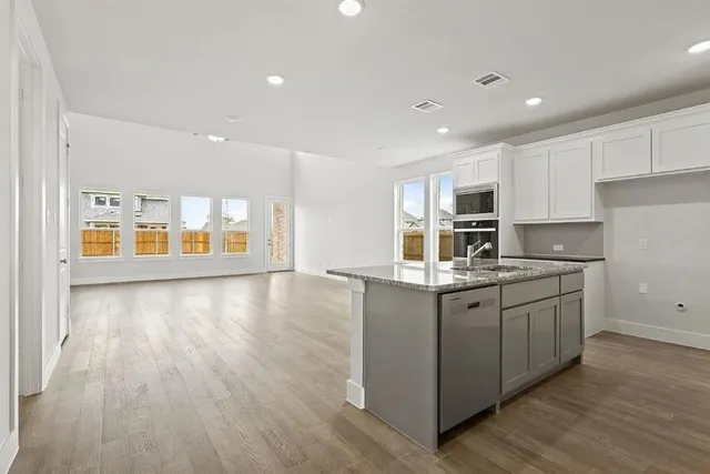 a kitchen with stainless steel appliances granite countertop a stove a sink and a microwave