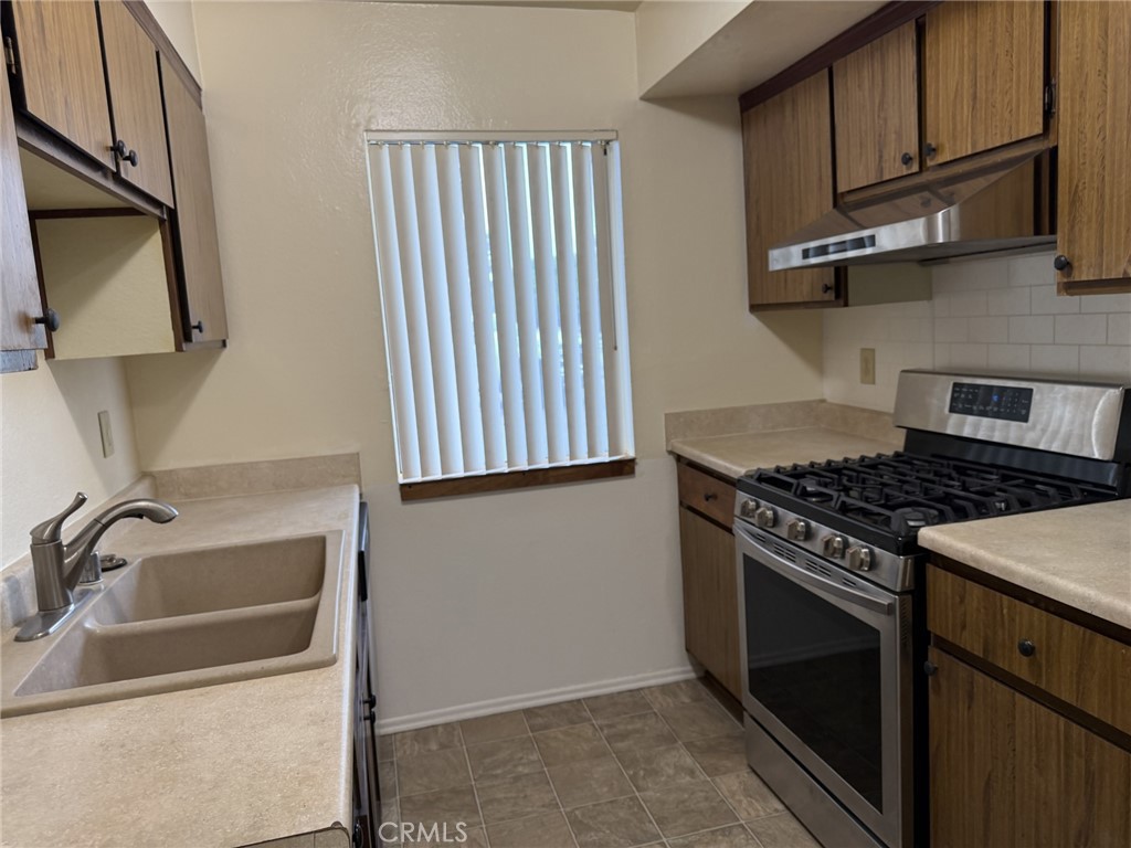 9090 Colony Place, Unit B Riverside, CA 92503 - Photo 4 of 19 a kitchen with granite countertop wooden cabinets stainless steel appliances and a sink