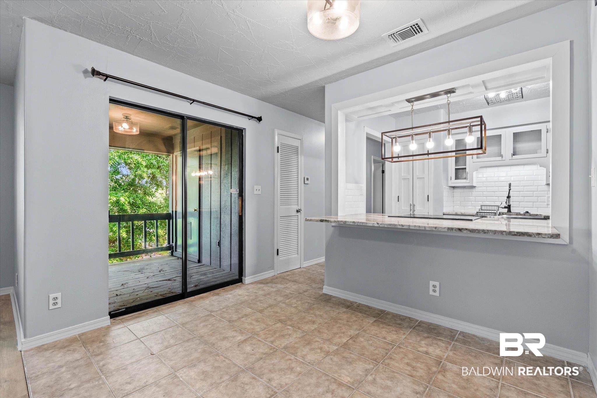 500 Grant Street, Unit C210 Daphne, AL 36526 - Photo 9 of 26 Tiled flooring extending throughout the space with a built-in breakfast bar featuring a stone countertop
