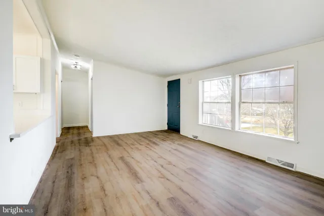 an empty room with wooden floor and windows