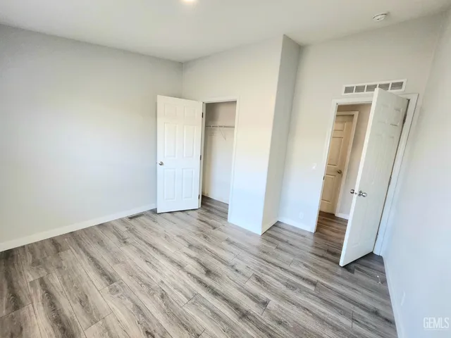 a view of an empty room with wooden floor and a bathroom
