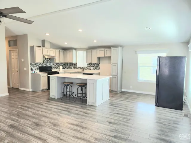 a kitchen with stainless steel appliances granite countertop a refrigerator a sink dishwasher a stove with wooden cabinets and floor