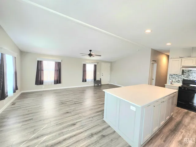 a large white kitchen with wooden floor and a fireplace