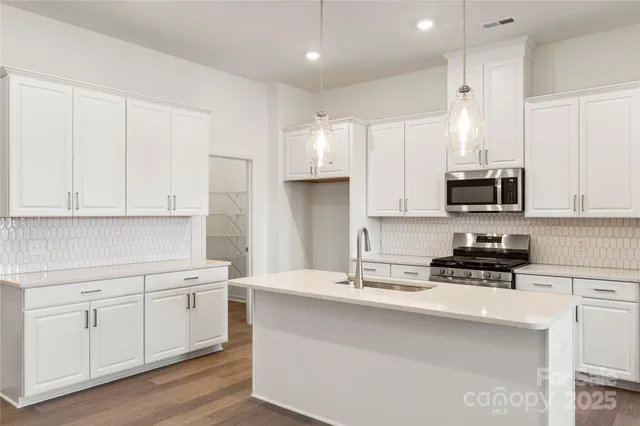 a kitchen with stainless steel appliances a sink stove and white cabinets