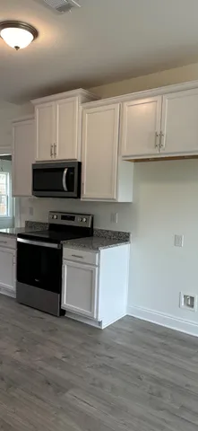 a kitchen with granite countertop white cabinets and black appliances