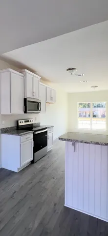 a kitchen with granite countertop white cabinets and wooden floor