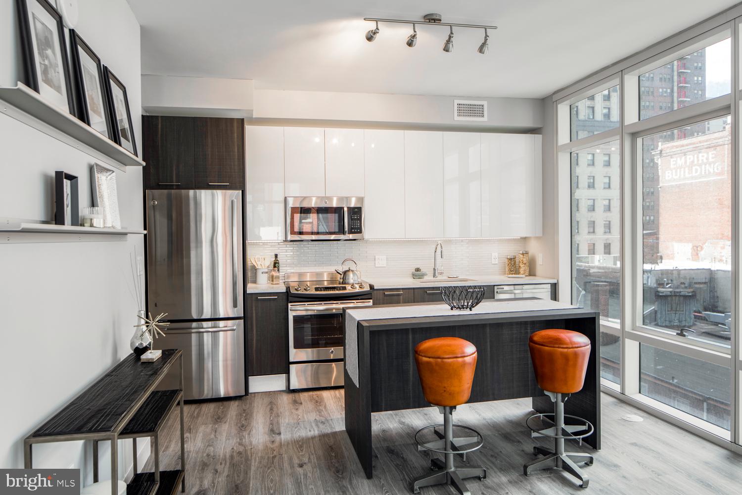 1213 Walnut Street, Unit 1909 Philadelphia, PA 19107 - Photo 2 of 36 a kitchen with stainless steel appliances granite countertop a stove top oven a refrigerator a dining table and chairs with wooden floor