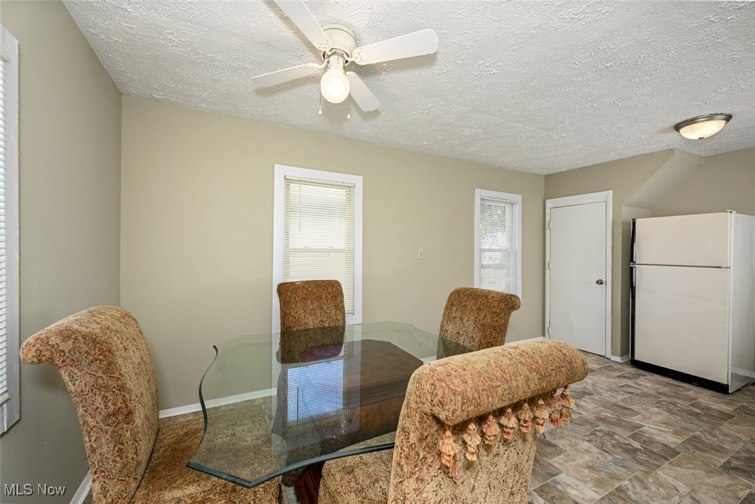364 Stanley Road Akron, OH 44312 - Photo 9 of 29 Dining room featuring a textured ceiling, stone finish floors, and a ceiling fan