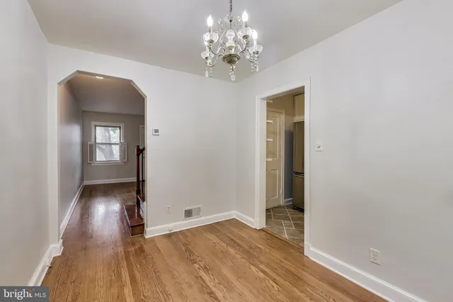 a view of a hallway with wooden floor and a chandelier