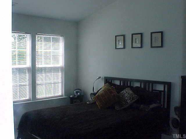 8443 Reedy Ridge Lane Raleigh, NC 27613 - Photo 5 of 10 a bed sitting in a bedroom next to a window and a chair