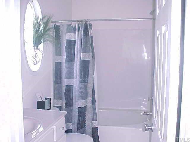 8443 Reedy Ridge Lane Raleigh, NC 27613 - Photo 6 of 10 a bathroom with a shower curtain and a sink