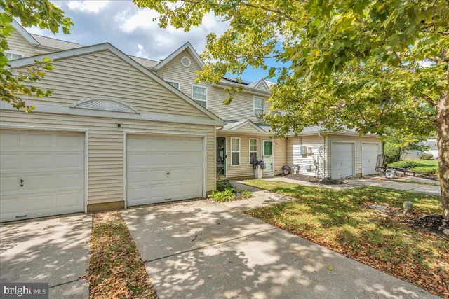 a front view of a house with a garden and trees