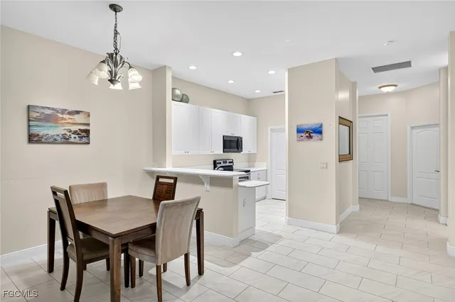 a kitchen with stainless steel appliances kitchen island granite countertop a dining table chairs and a refrigerator