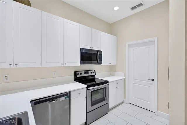 a kitchen with white cabinets and stainless steel appliances