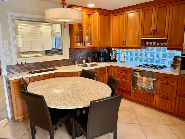 a kitchen with stainless steel appliances granite countertop a table chairs sink and cabinets