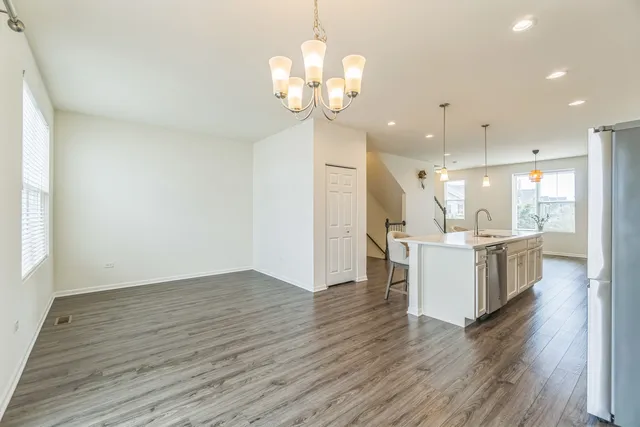 a open kitchen with a refrigerator and a chandelier