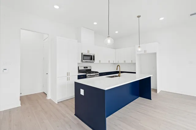 a kitchen with kitchen island a sink stainless steel appliances and wooden floor