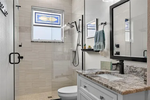 a bathroom with a granite countertop sink toilet and shower