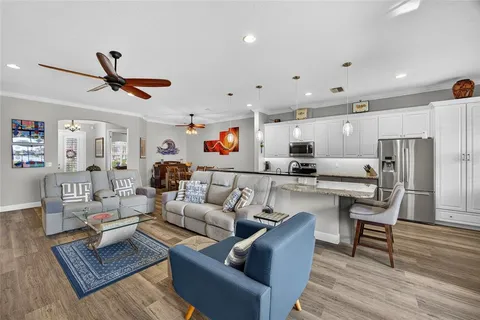 a living room with furniture kitchen view and a wooden floor