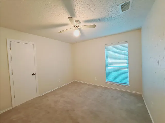 an empty room with windows and fan