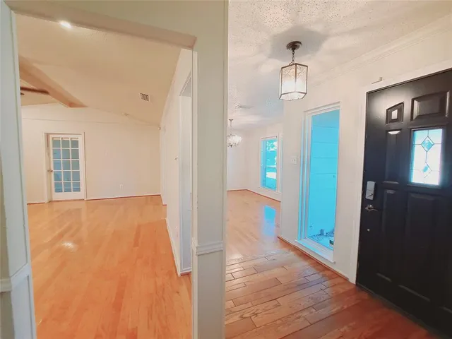 a view of an empty room with wooden floor and a bathroom