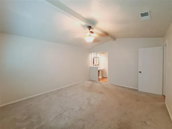 an empty room with chandelier fan and windows
