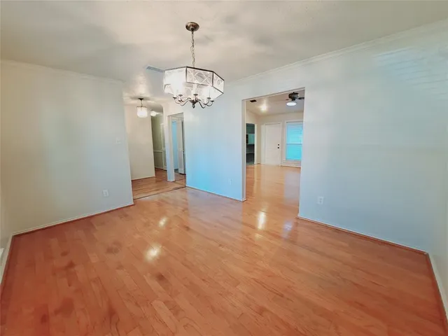 a view of a hallway with wooden floor and chandelier