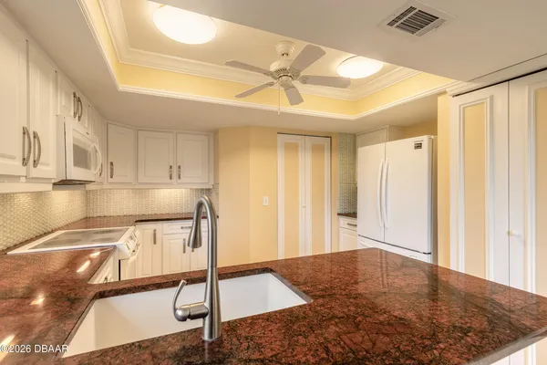a kitchen with stainless steel appliances granite countertop a stove a sink dishwasher and a view of living room